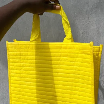 Bright yellow tote bag with horizontal ribbed texture and yellow loop handles, standing upright