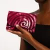 Hand holding an Ankara African print card holder with pink swirl design, showing compact size.