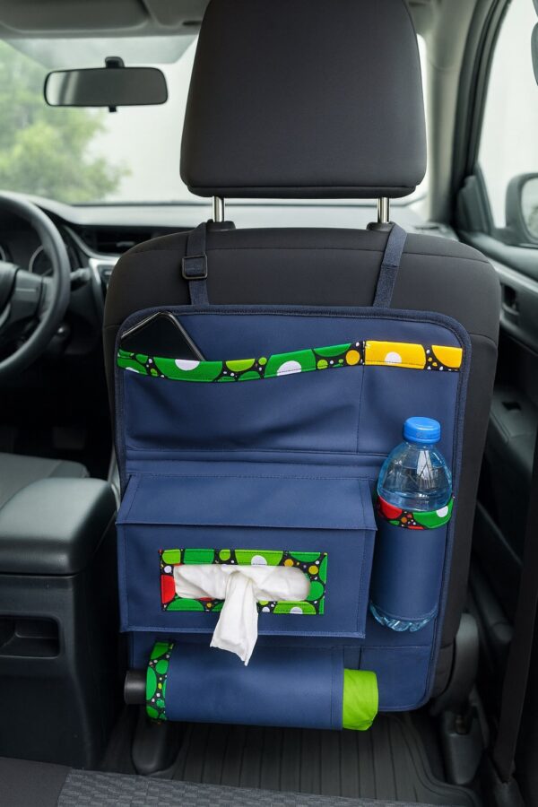 Full view of navy blue car organizer with green, yellow, red Ankara trim, mounted on car seat with compartments for bottle, tissue, and phone.