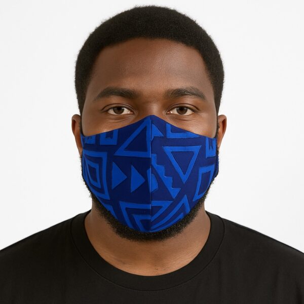 Close-up of a man wearing a blue Ankara face mask with geometric triangle and arrow patterns. Front view on white seamless background.