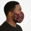 Side profile of a man wearing a red and black geometric Ankara print face mask. High-contrast patterns with a clean white background.
