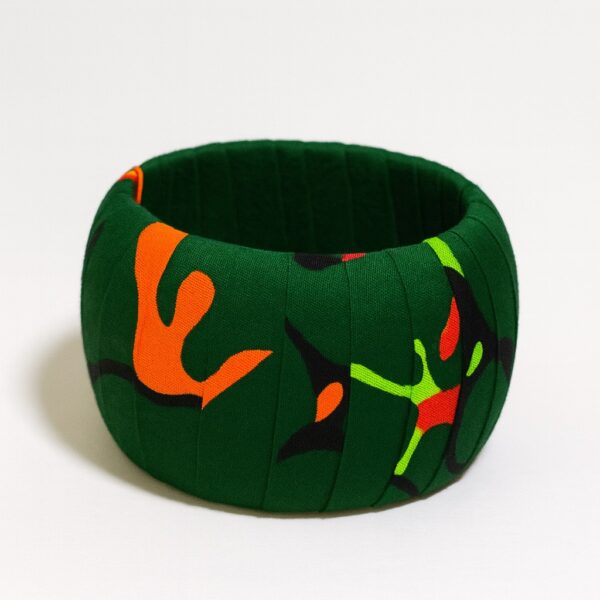 Deep green Ankara print bangle with abstract orange, red, and lime green leaf-like shapes on fabric.