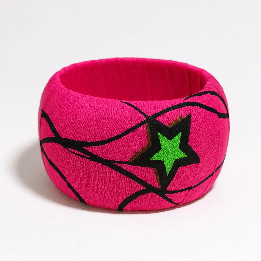 Bold pink Ankara bangle with a large green star and flowing black line patterns, placed on a white background.