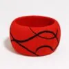 Red Ankara bangle featuring smooth black swirl lines in a minimalist pattern, placed on a plain white background.