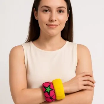 Caucasian woman in a sleeveless ivory top wearing a pink star Ankara bangle and yellow bangle on her wrist.