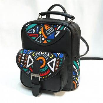 Studio product shot of a black leather backpack with bold geometric Ankara print flap and side pocket.