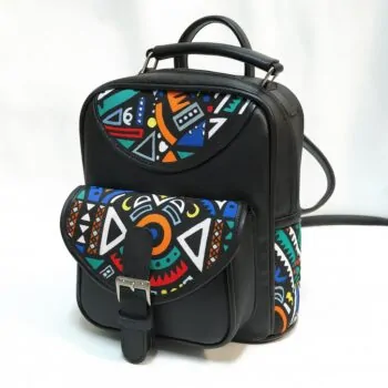 Studio product shot of a black leather backpack with bold geometric Ankara print flap and side pocket.