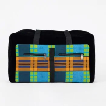 Front view of a collapsible duffel bag with bold African Ankara print in blue, orange, and green checkered patterns, dual front zip pockets, and black canvas base with short black handles. Studio white background.
