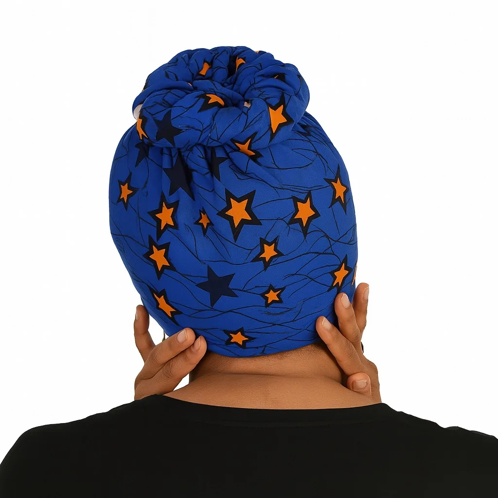 Woman wearing a blue Ankara headwrap backview with black and orange star patterns, smiling.