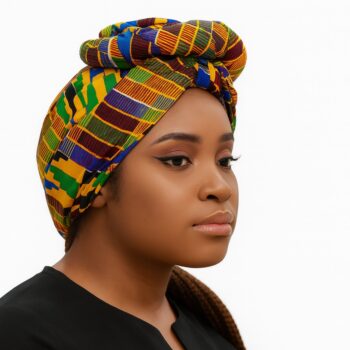 Side profile of a woman wearing a colorful Kente-inspired Ankara headwrap with bold stripes.