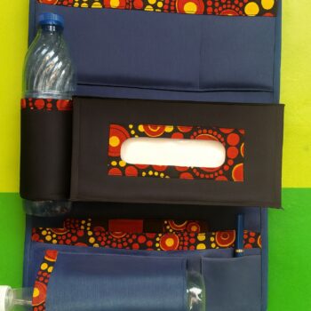 Vibrant Ankara print car seat organizer with bold red and yellow circle patterns, fitted with bottle holder and tissue compartment.