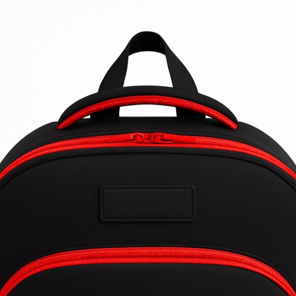 Close-up of the top handle and zipper section of a durable black customizable school backpack with red trim, showing reinforced stitching and double zipper design.