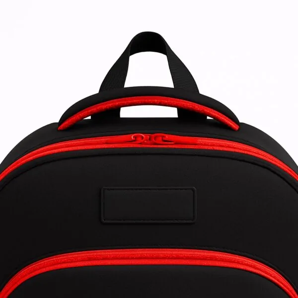Close-up of the top handle and zipper section of a durable black customizable school backpack with red trim, showing reinforced stitching and double zipper design.