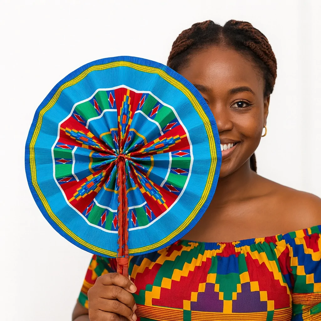 Smiling African woman holding a blue African print hand fan that covers half her face. She wears a matching Kente-style off-shoulder top against a white background.