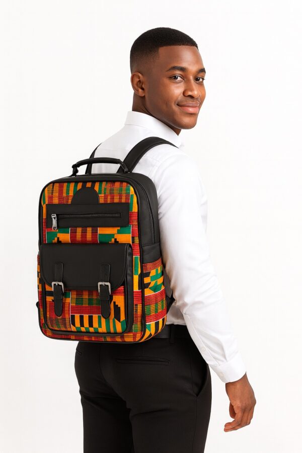 Man wearing large African print backpack – A well-dressed young African man in a white dress shirt and black trousers, smiling while carrying a large Kente-pattern backpack with black leather pockets and silver buckles.