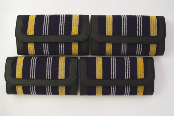 Four African print Ankara ladies' purses – navy background with gold and silver vertical stripes, trimmed with black leather, arranged in two rows on a white background.