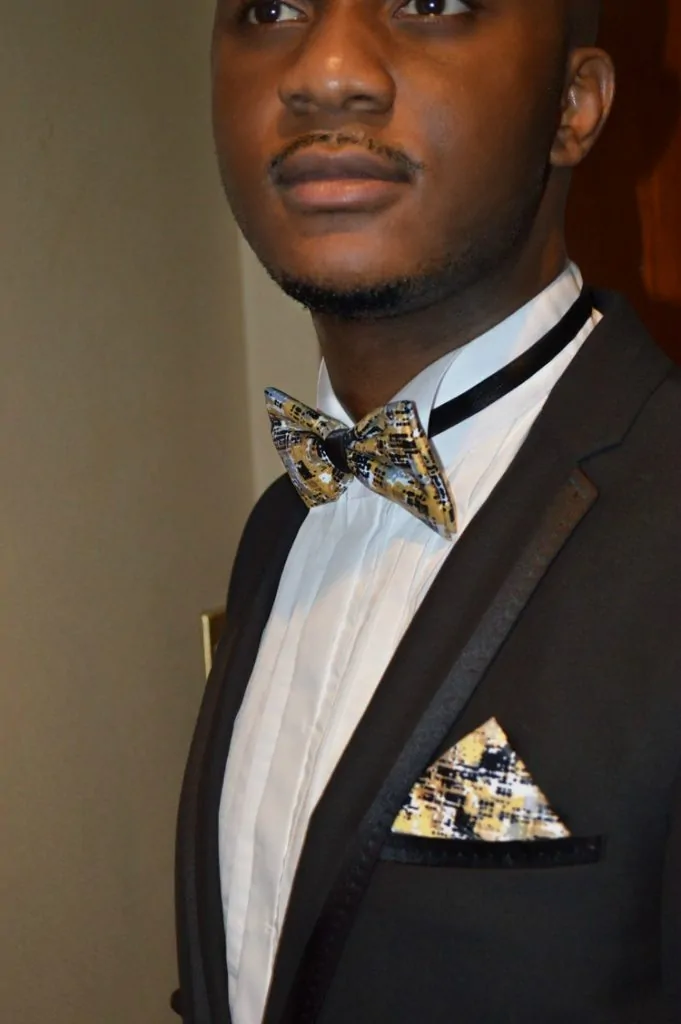A man with a suit wearing an African print bow tie.