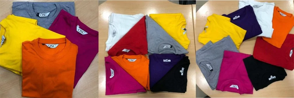 Multiple plain t-shirts with different colors placed on a table.