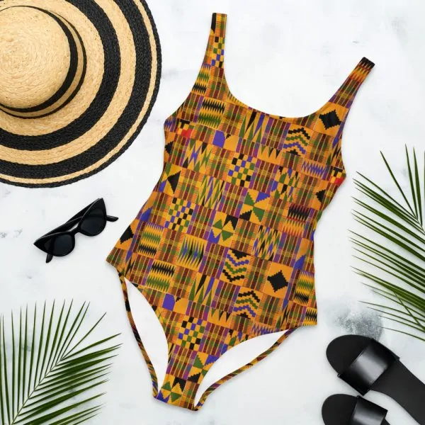 African print beach wear, hat, a slipper, and eyeglass on a white surface.