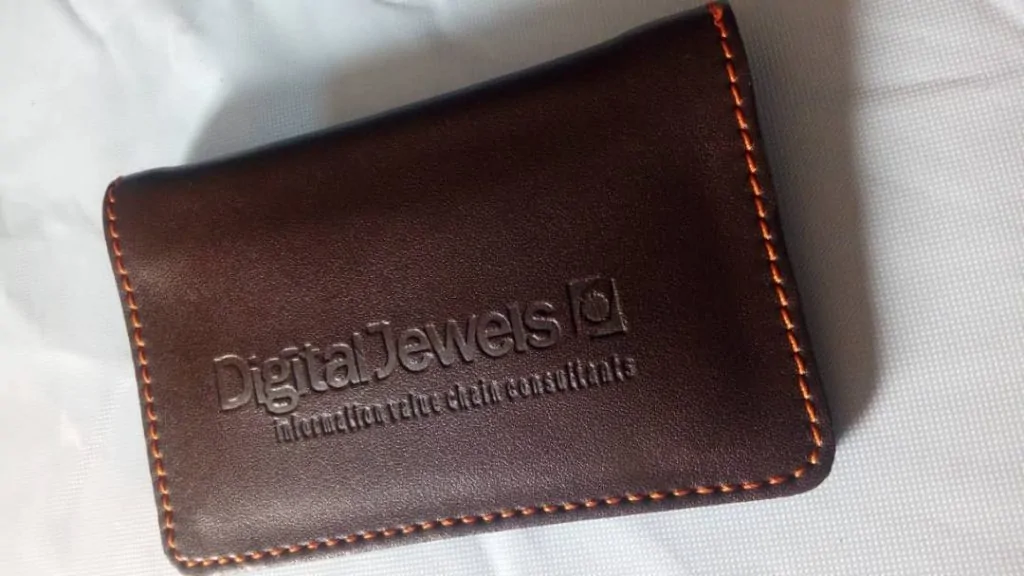 Brown leather card holder with a business name inscribed on it.