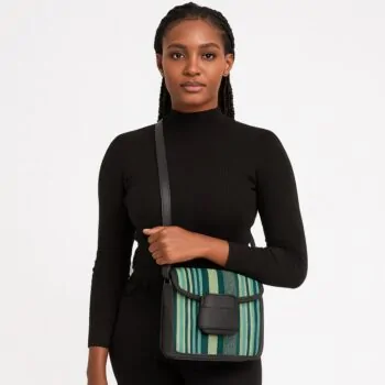Beautiful African woman in black holding a green-striped Aso Oke side bag with black leather flap and crossbody strap.