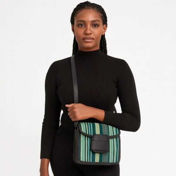 Beautiful African woman in black holding a green-striped Aso Oke side bag with black leather flap and crossbody strap.