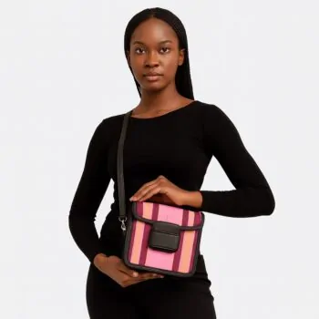 Stylish African woman in black top posing with a vibrant pink and purple Aso Oke side bag, held at waist level.
