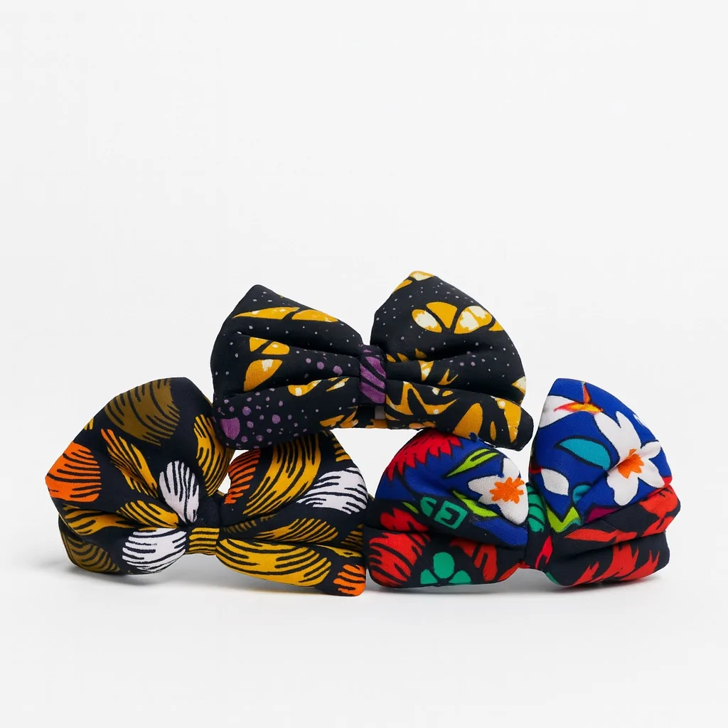 Three colorful Ankara fabric bows with floral and abstract patterns on a white background.