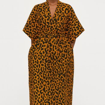 Woman wearing an orange and black leopard print kimono, standing barefoot.
