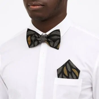 Man wearing black and gold African print bow tie and pocket square with white shirt.