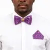 Man wearing purple African print bow tie and matching pocket square with white shirt.