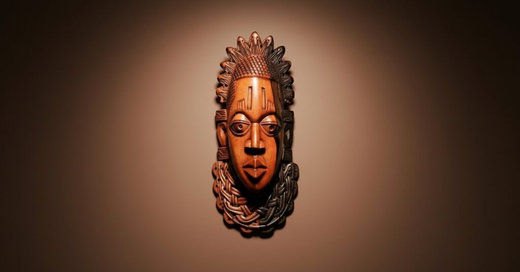 A dramatic spotlight on a carved wooden Benin mask, a powerful piece of African wall decor for living room wall, shown against a dark, moody background.