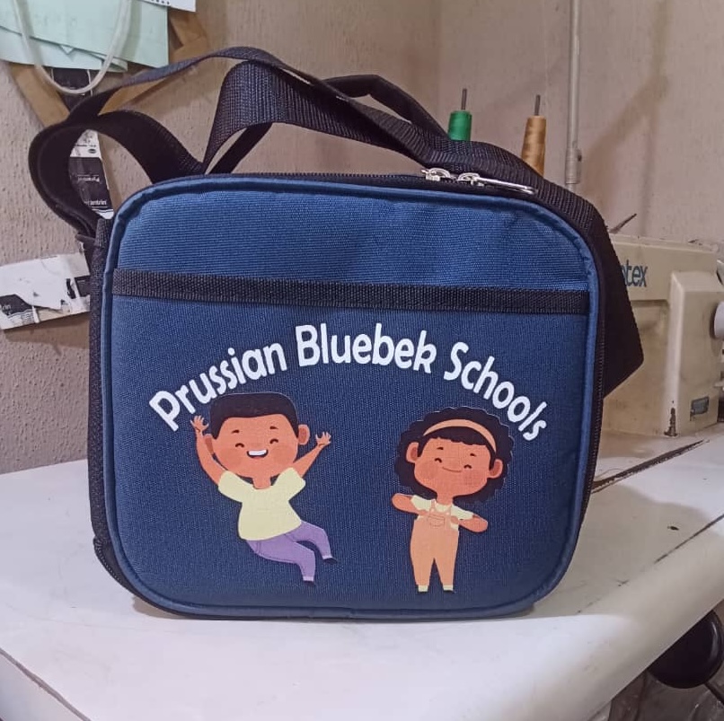 See how African Things produced 123 branded backpacks and lunch boxes for Prussian Bluebek Schools. Bulk school bag and lunch box manufacturing for schools in Nigeria.